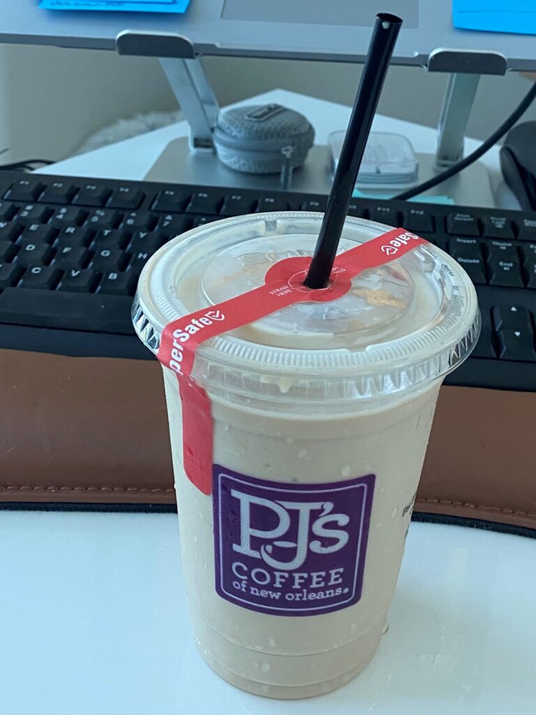 Iced coffee on teacher's desk in front of computer keyboard.