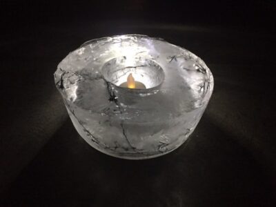 A small ice candle holder has a tea light in it for a winter science experiment 