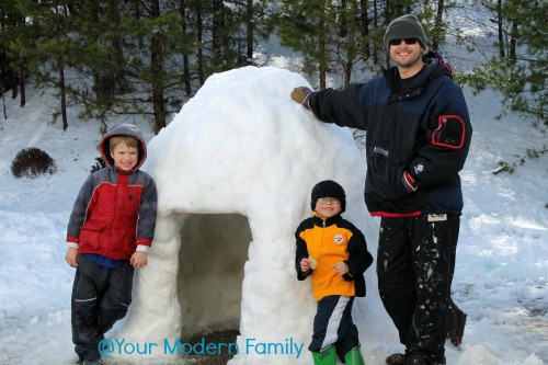 family standing near an igloo that they built for a snow activity 
