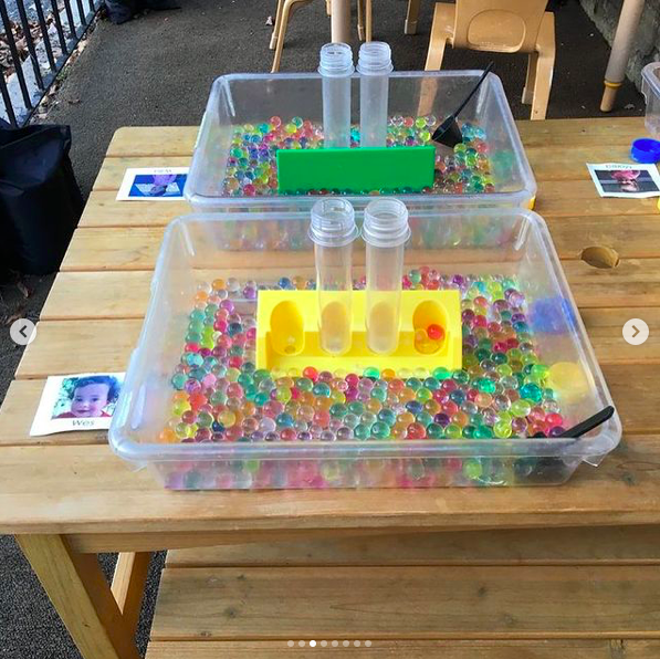 Sensory tubs with water beads and plastic containers labeled with children's photo name cards for individual sensory play in the classroom