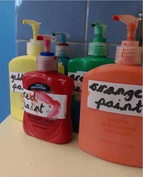Instagram-worthy teacher hacks include storing paint in old soap containers as seen here with red, yellow, blue, green, and orange paint.