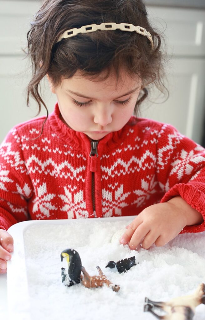 girl playing in snow sensory bin 