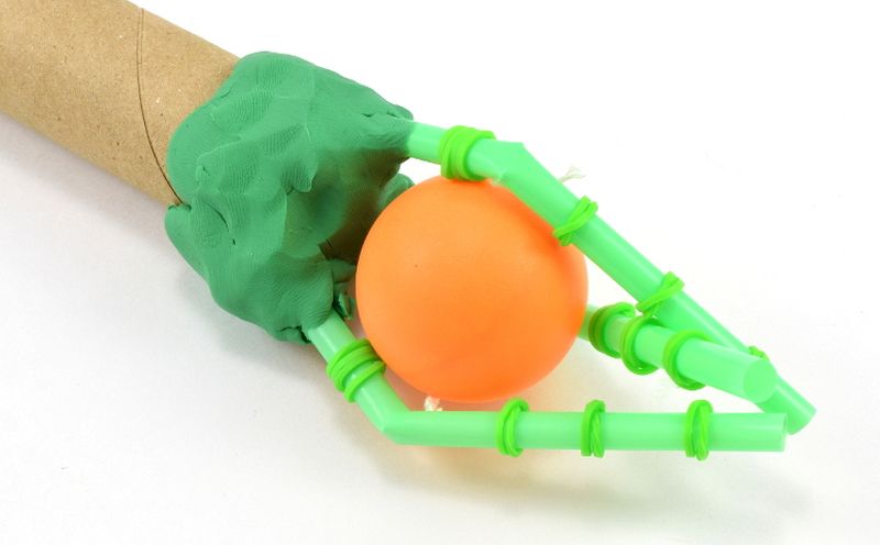 Mechanical hand made from supplies like drinking straws, clay, and cardboard