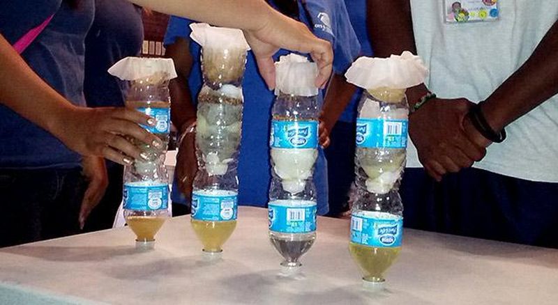 Kids using plastic bottles and paper to create a new type of water filter