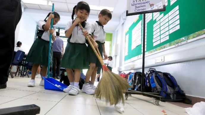 Young students in a Japanese classroom sweep the floor