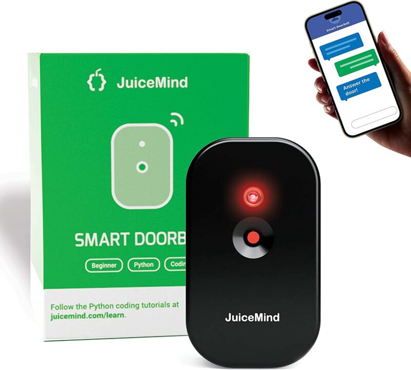 Coding toys like this one use a smartphone to create something. A green box is in the background. A hand holding a phone is shown and a black smart doorbell is in the forefront.