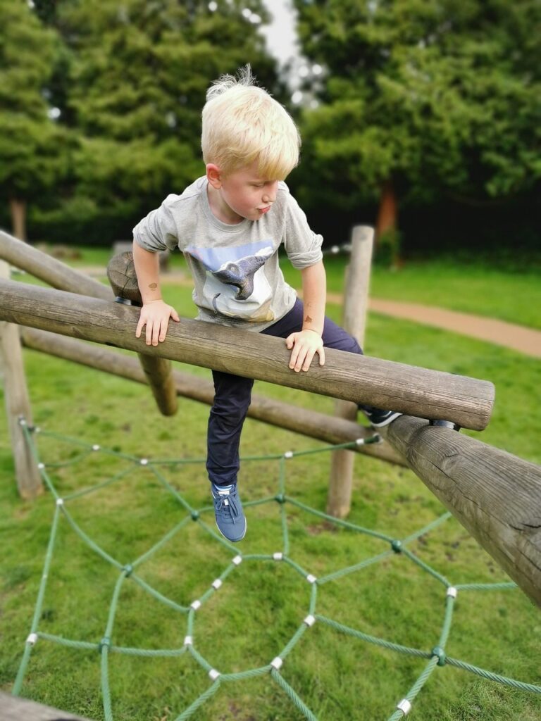 Little kid climbing on playground equipment, as an example of gross motor skills.