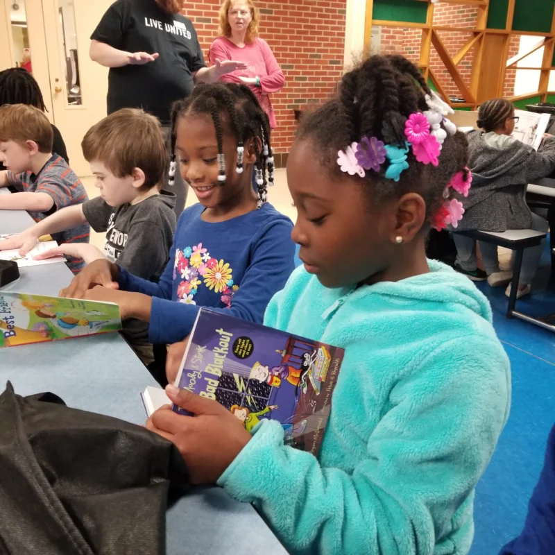 Children browsing through books laid out on tables