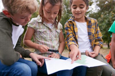 Group Of Children On Outdoor Activity Camping Trip Looking At Map Together