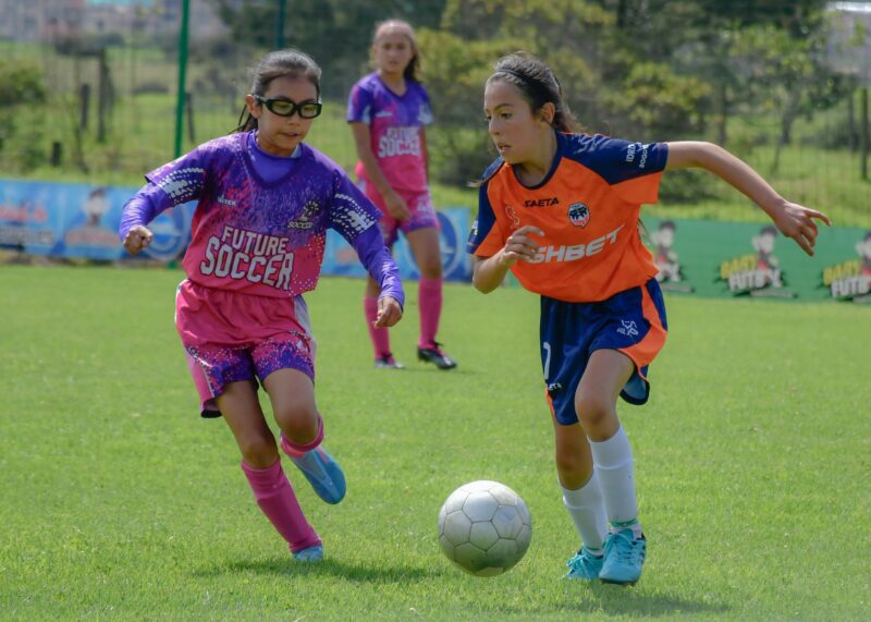 Three elementary school girls playing in a soccer game.