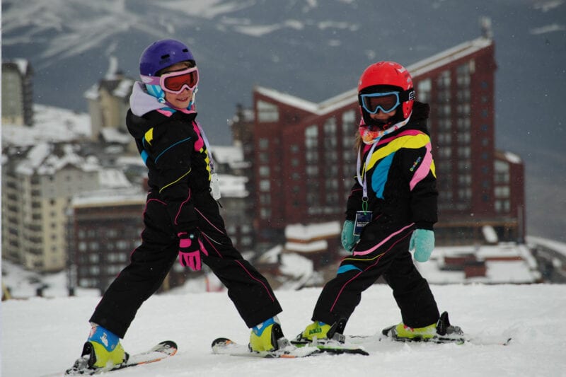 Children in their ski suits on top of the mountain