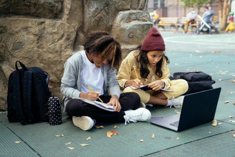 Two students writing in the schoolyard as an example of outside time for kids