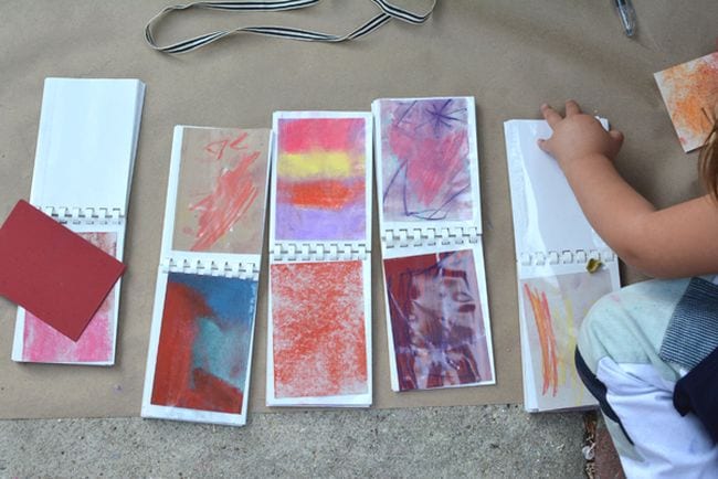 Child sliding pastel art into mini photo album pages (Kindergarten Art)