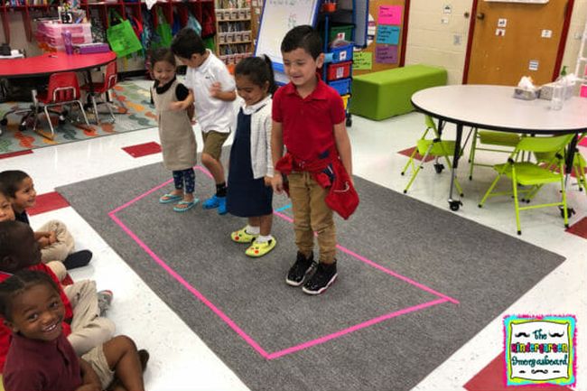 Children standing inside tape lines on the floor representing a boat, playing kindergarten math games