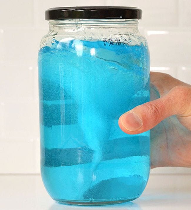 Mason jar of blue water, with a tornado-like shape showing inside