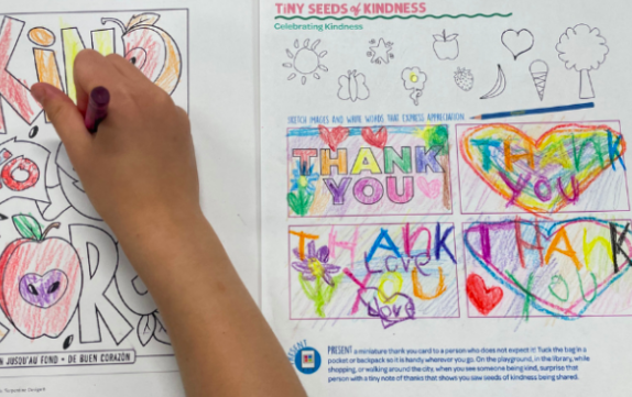 A child's hand is seen coloring a kindness worksheet as an example of fun last day of school activities