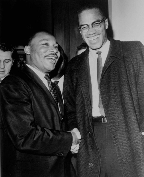 Martin Luther King Jr. and Malcom X are shown shaking hands and smiling