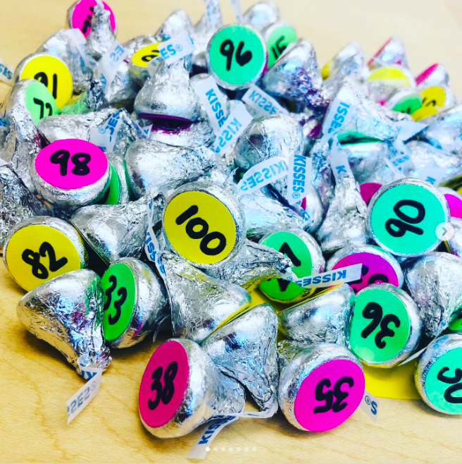 A pile of Hershey's kisses, each with a colorful number sticker on the bottom