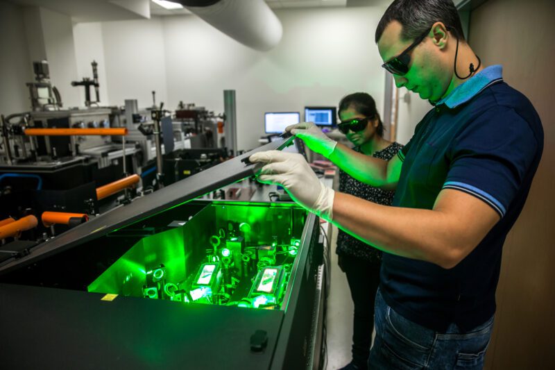 Multi-ethnic Group of Researchers Using Powerful High Frequency Laser used for new materials research.