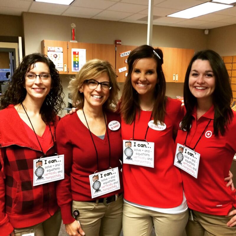 Four teachers are shown wearing red shirts with signs around their necks about learning targets.