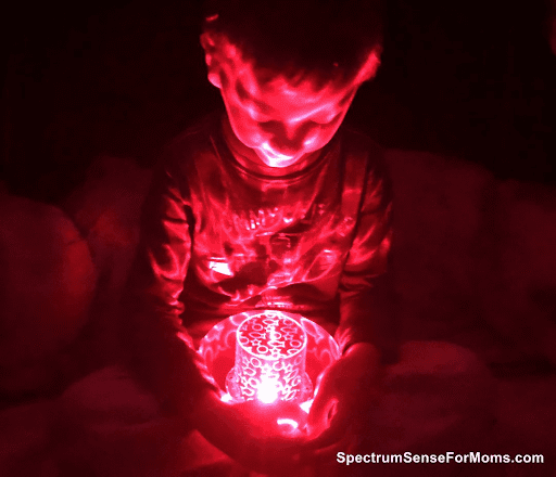 Kid holding a light projector emitting red light- sensory room 