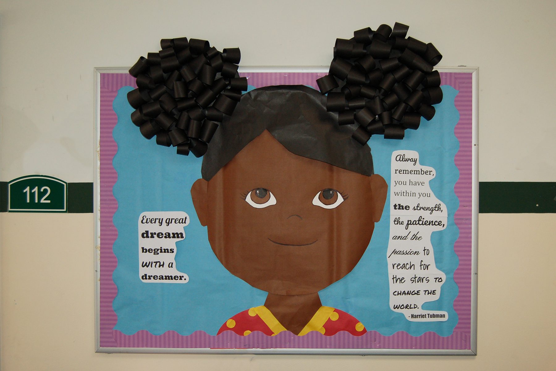 A bulletin board is designed to look like a little girl from the shoulders up. It has a quote by Harriet Tubman to the right of the girl.