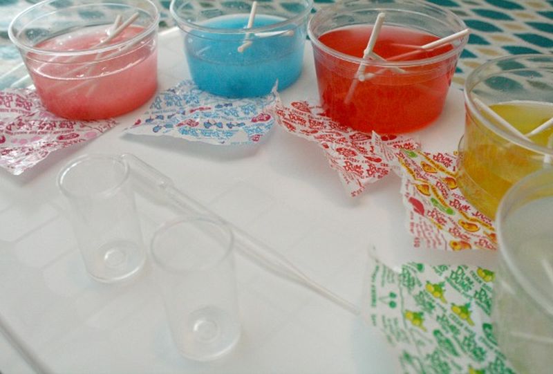 Plastic cups filled with water and different flavors of DumDum lollipops