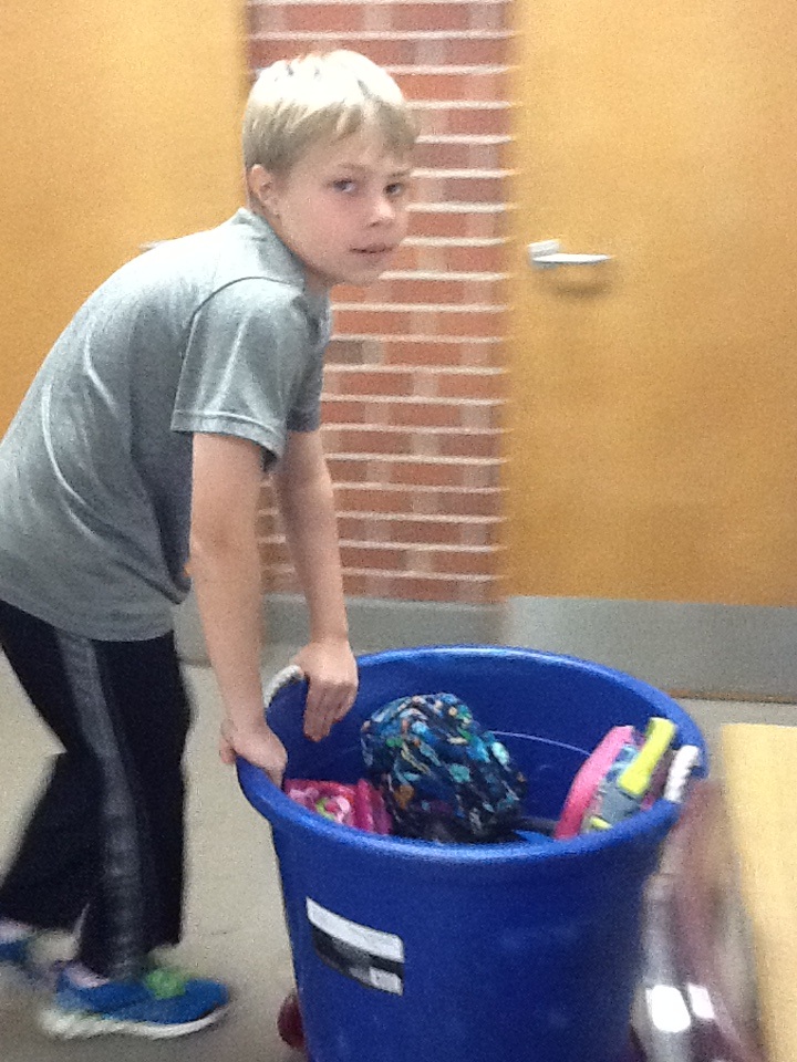 Student carrying blue bin filled with lunch bags