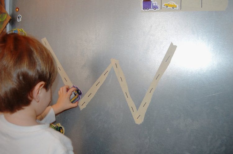 The letter W taped with masking tape onto a metal board