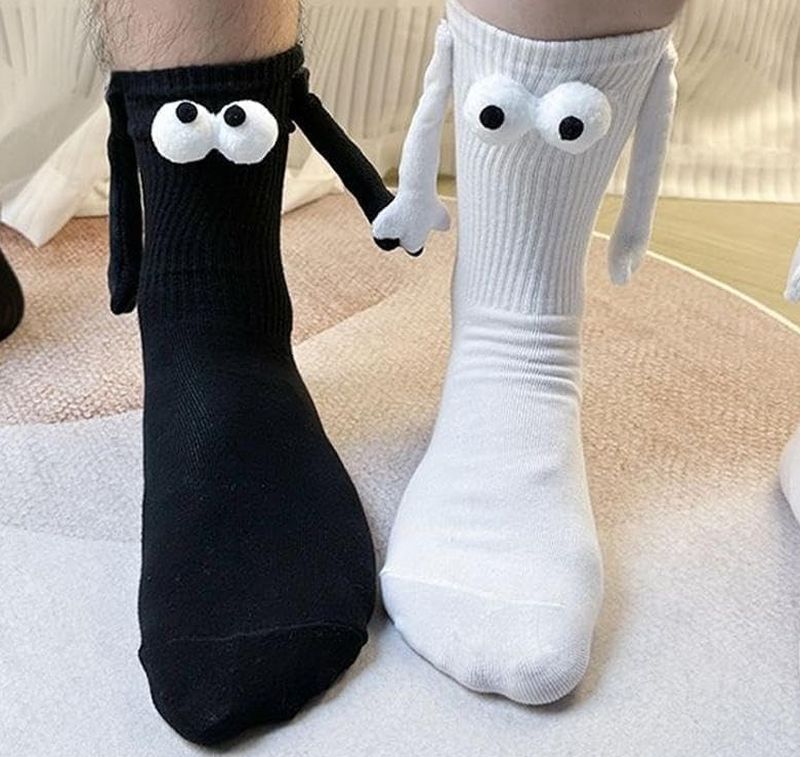 Black sock and white sock with wiggly eyes and small arms attached together by magnets