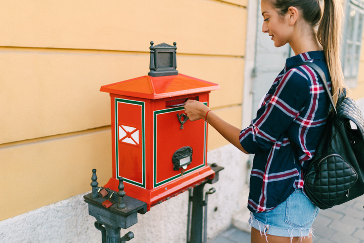 A teen dropping a letter into a red mailbox - life skills for teens