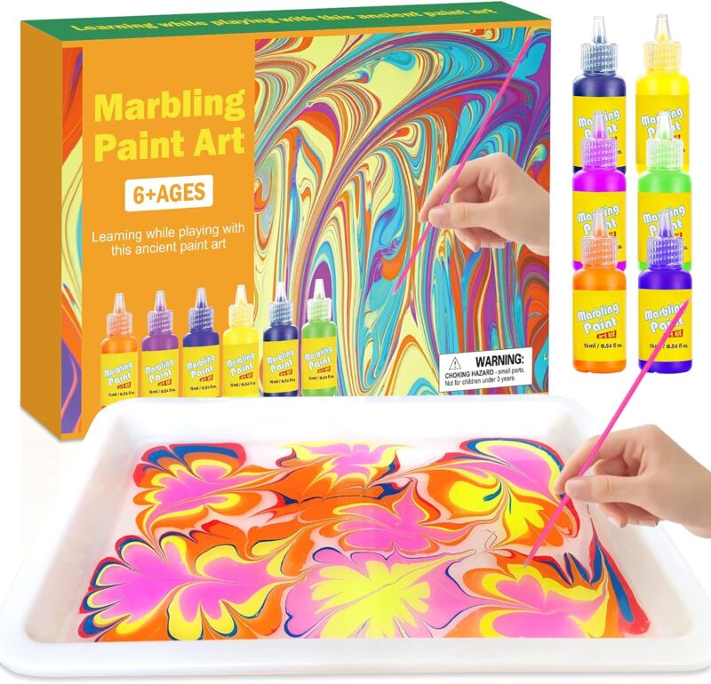 A try has paint swirled in it and a stick is dipped into it.