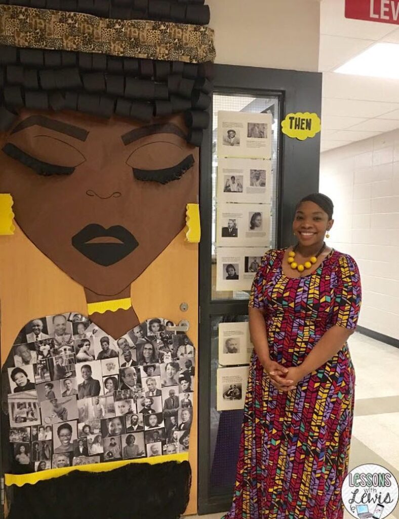 Black teacher standing by her classroom door decorated with a Black woman's head made of construction paper