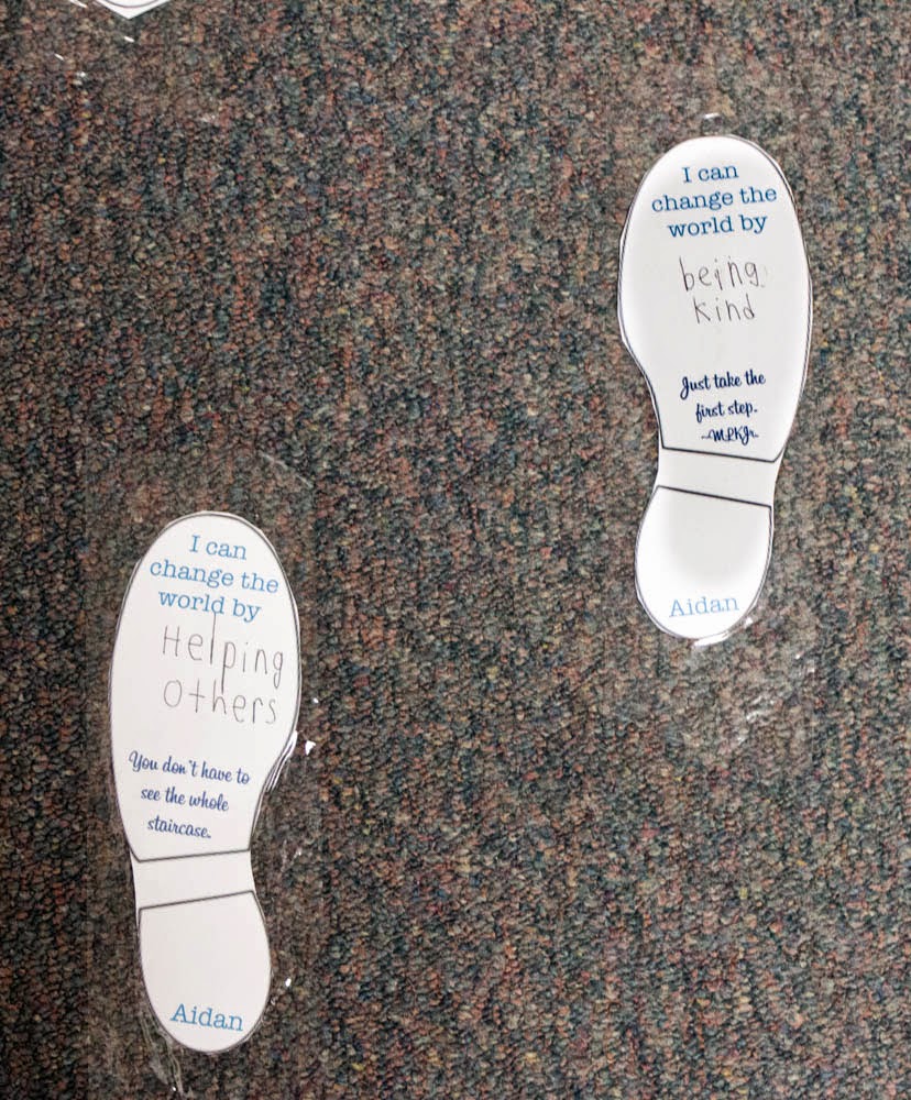 Foot prints taped to the floor with inspiring Martin Luther King Jr quote and kids' ideas for how they can change the world for the better