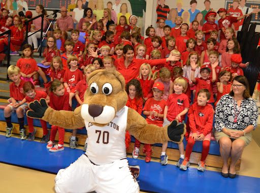 School mascot posing with students, as an example of pep rally activities and games