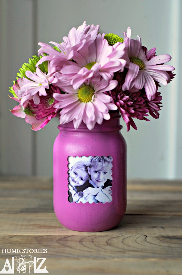 A mason jar is painted purple with a photo of children on it.
