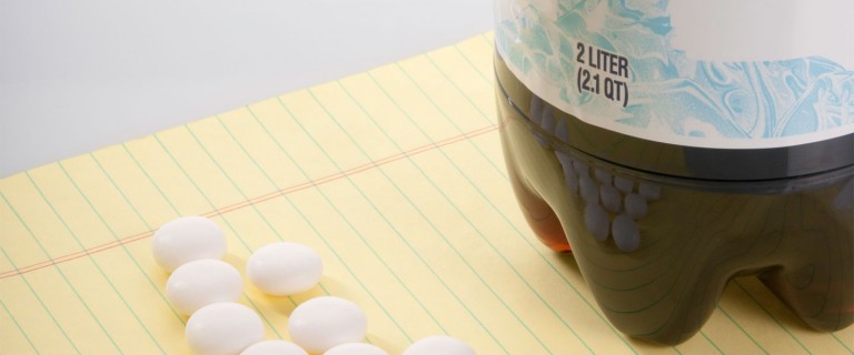 Photo of mentos candy and the bottom of a soda bottle placed on yellow notebook paper to show materials used in the mentos geyser second grade science classroom.