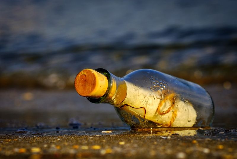 Glass bottle on a seashore with a rolled up paper inside