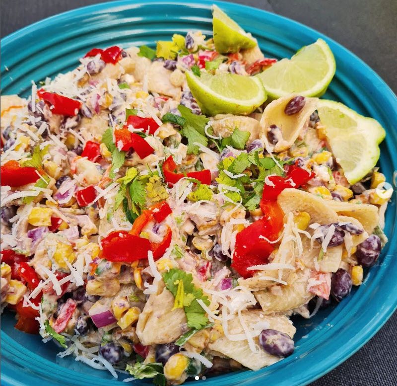 Teal bowl filled with Mexican pasta salad and garnished with lime
