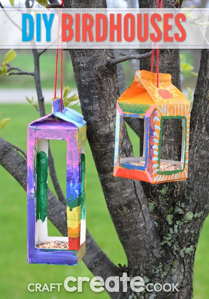 Colorful bird houses made from milk cartons hang from a tree