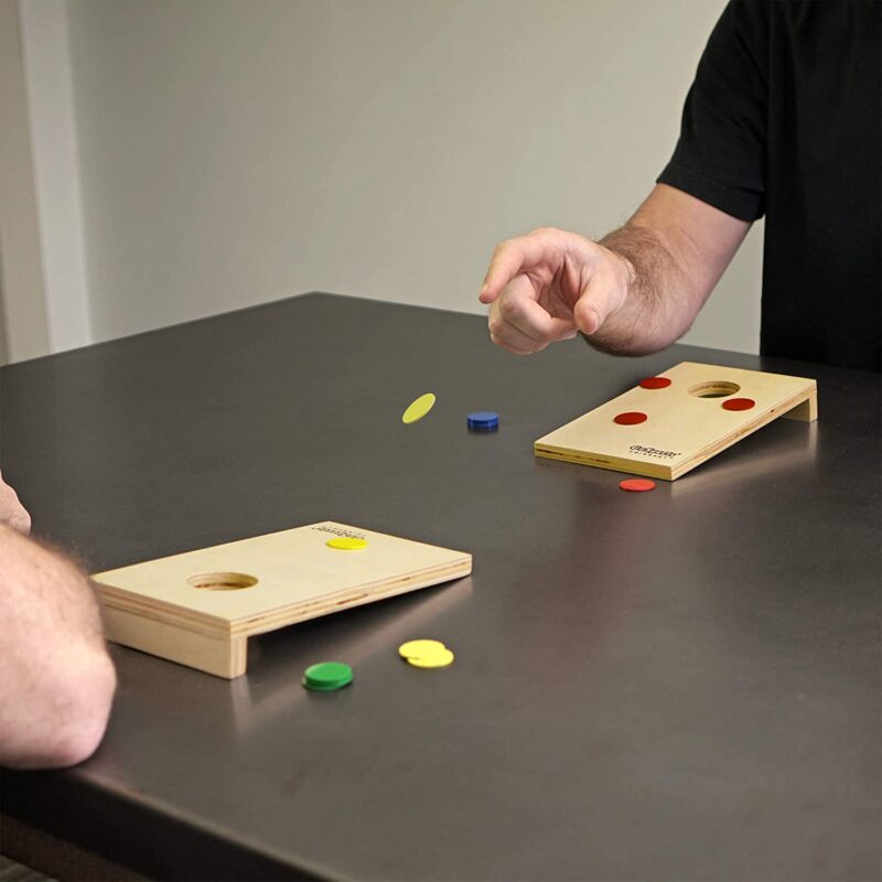 Two people playing a tabletop version of cornhole game