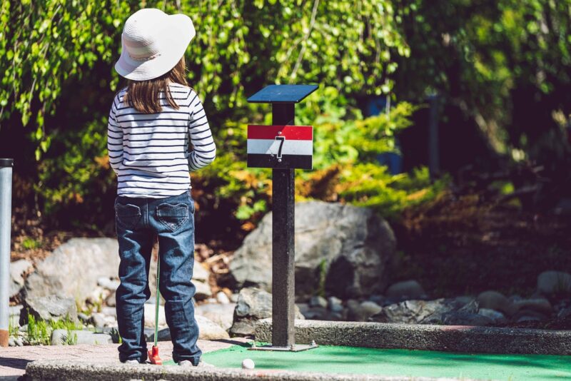 girl standing on miniature golf course for experience gift idea 