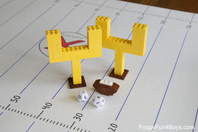 A pair of leg goal posts, a lego football and a pair of dice on top of a worksheet
