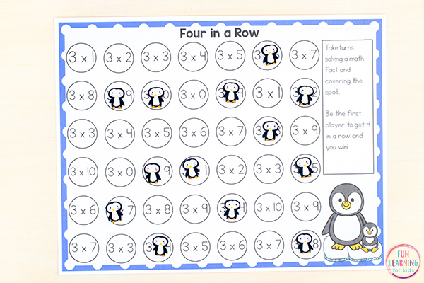 A worksheet with many circles with multiplication problems in them, a few covered with penguin stickers 