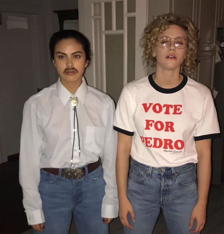 One character has brown hair and glasses and a white shirt that says vote for pedro. The other character has a western themed shirt on and a fake moustache.