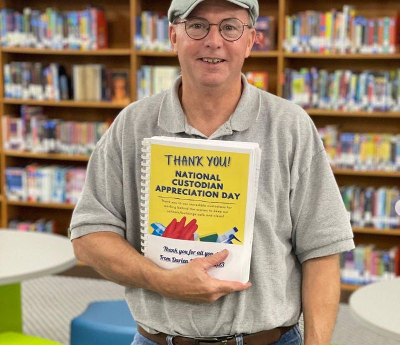Custodian holding a spiral-bound book of thank you notes 