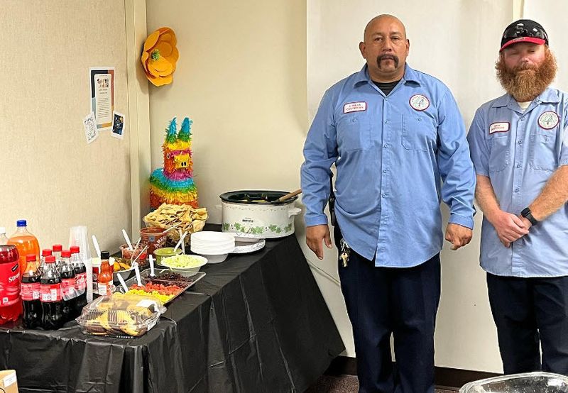 School custodians standing by a nacho bar set up for National Custodian Day