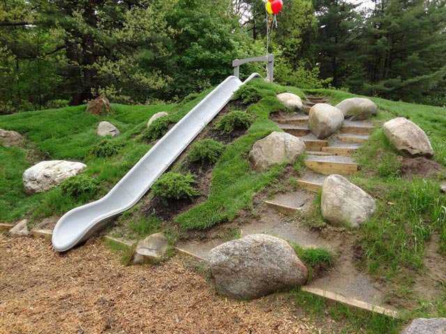 slide and stairs on a hill with grass for a natural playground 
