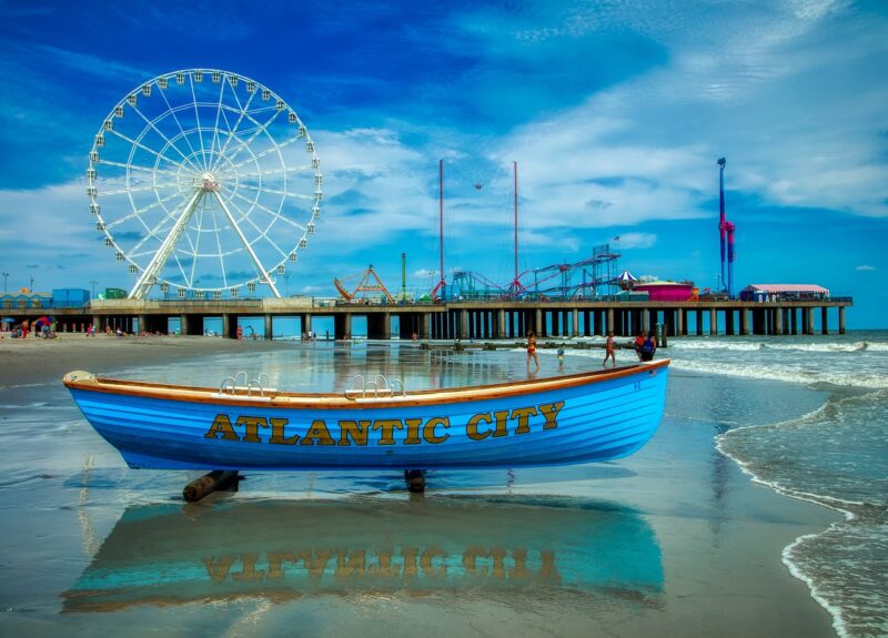 Boat and Ferris wheel on boardwalk in Atlantic City, NJ, a state with a high average teaching salary