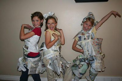 three girls modeling outfits made from newspaper